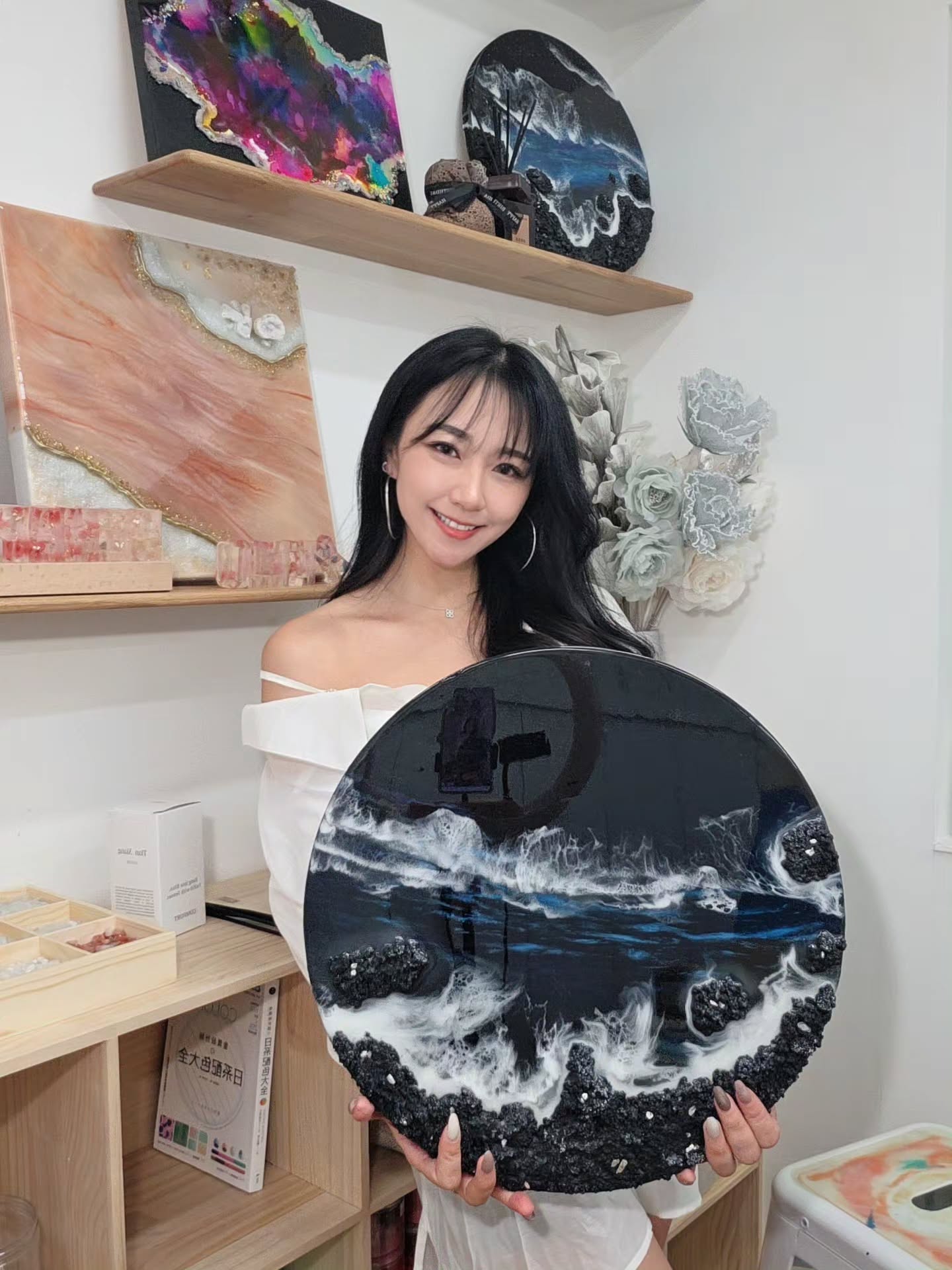 Elaine 在工作室展示親手創作的海浪掛畫